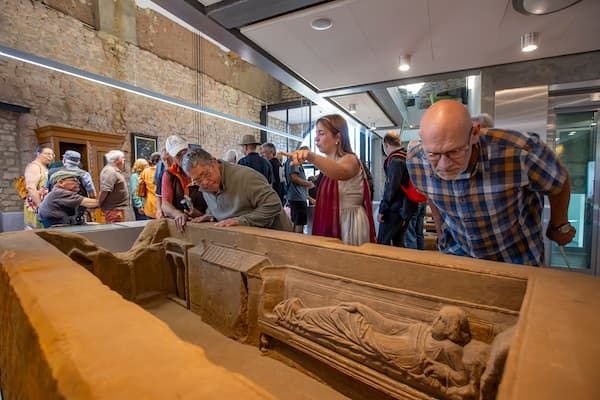 Bezoekers bekijken de askist tijdens de opening van het Romeins Infocentrum Overhuizen