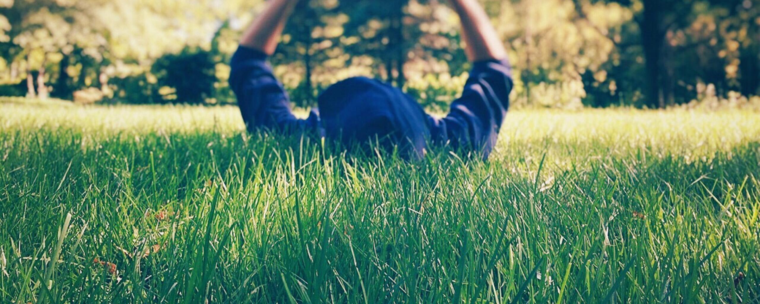 Young people enjoy lying in park with book