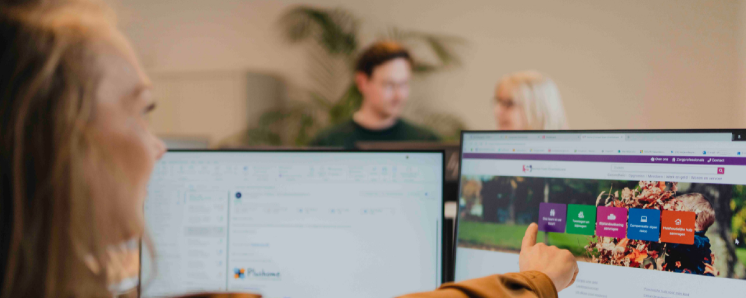 medewerker vanachter bureau wijst het computerscherm aan