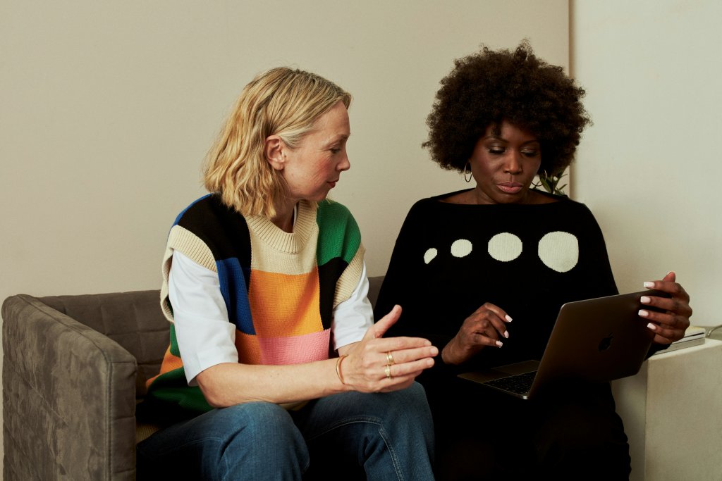 Twee vrouwen op een bank kijkend naar een tablet.