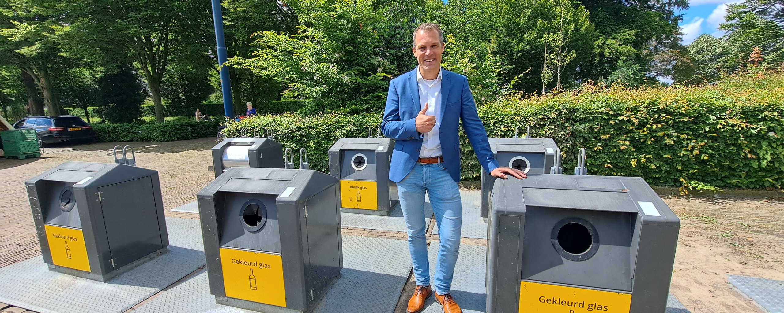 Wethouder Bos tussen de ondergrondse containers op het marktplein