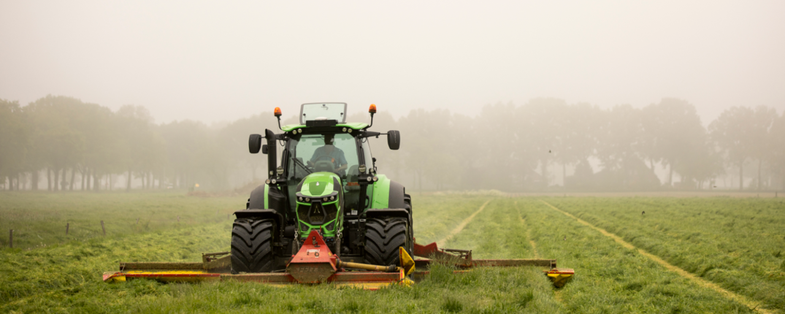 Tractor met maaier op grasland