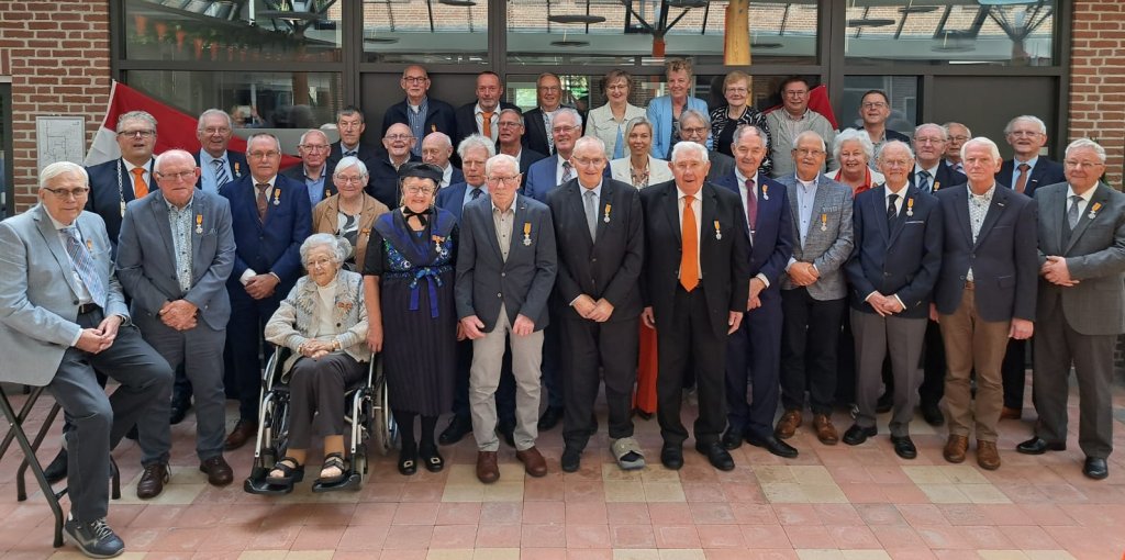 Groepsfoto van alle gedecoreerden bijeen in het gemeentehuis.