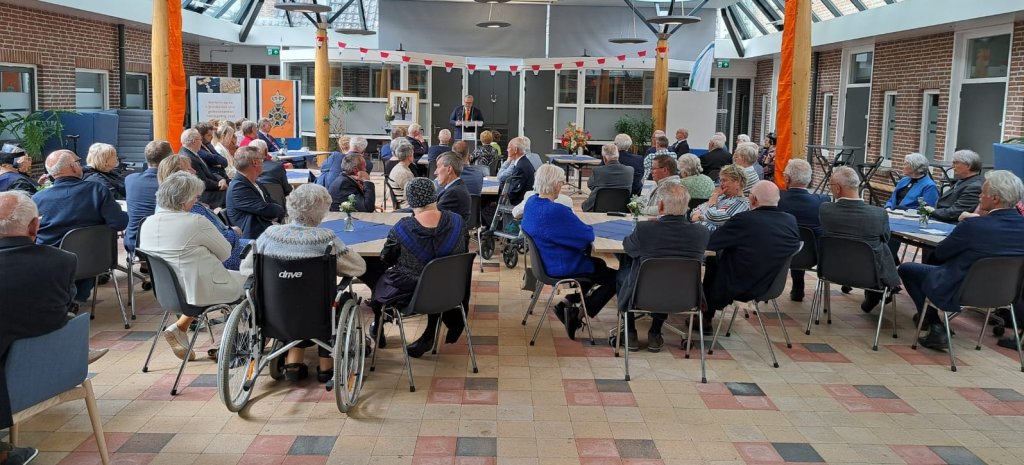 De gedecoreerden bijeen in het gemeentehuis. Burgemeester Ten Kate houdt een toespraak.