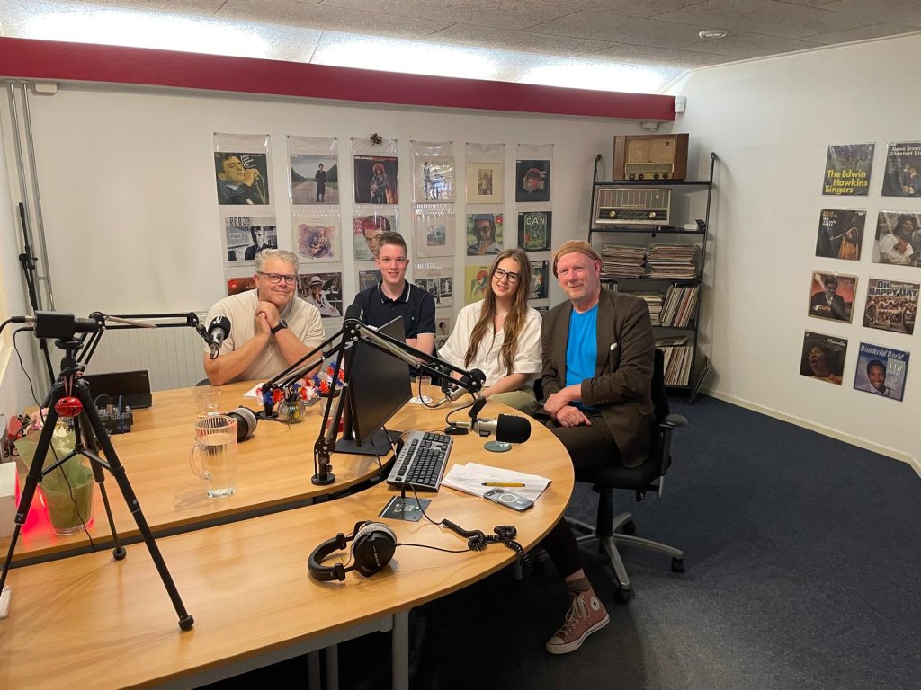 Groepsfoto in de radiostudio. Van links naar rechts: burgemeester Jan ten Kate, Jarnick Roo van een lokaal ICT-bedrijf, Dieunée Knoll van de politie en gespreksleider Albert Bartels.