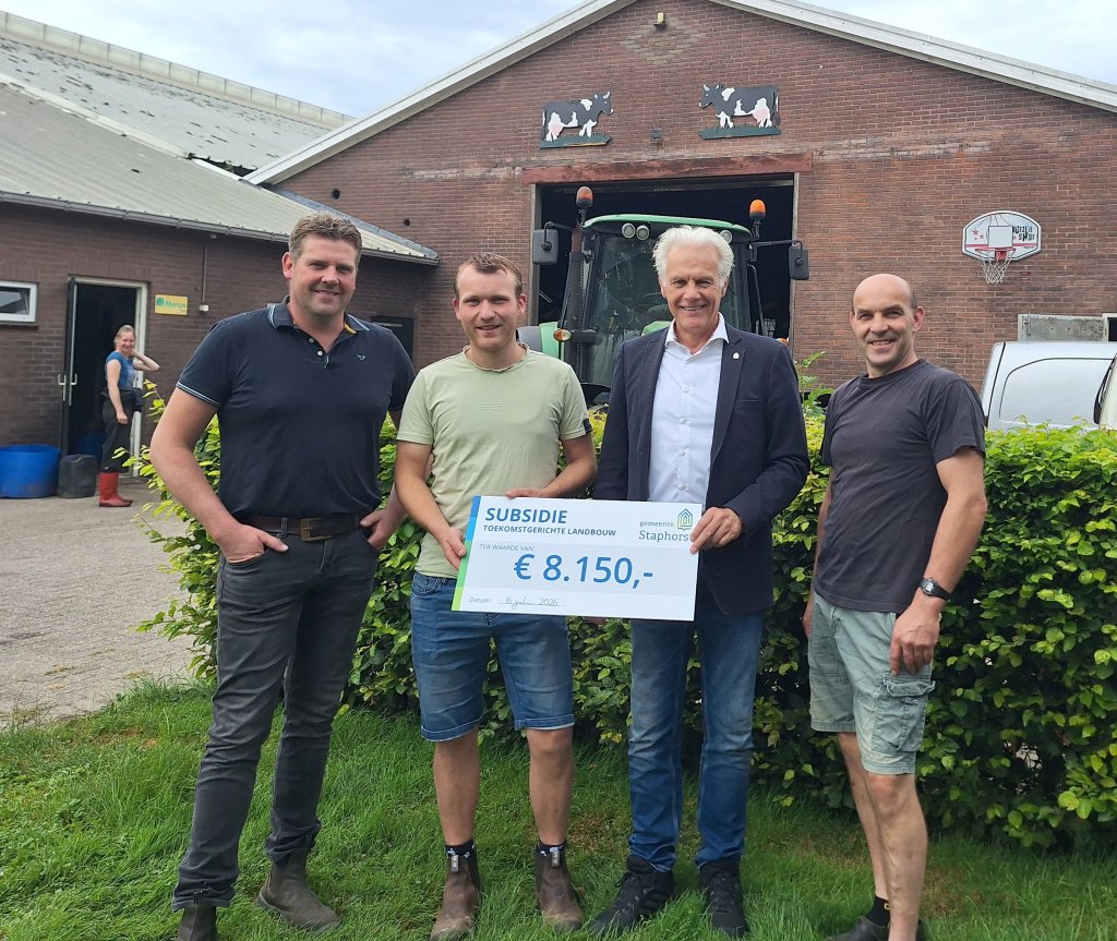 Wethouder Mulder overhandigt symbolisch een cheque op het erf van de mede-initiatiefnemer firma Haasjes. De andere bedrijven in dit project zijn maatschap R. en J. Wildeboer, Kruidhof Agro en melkveebedrijf Visscher.