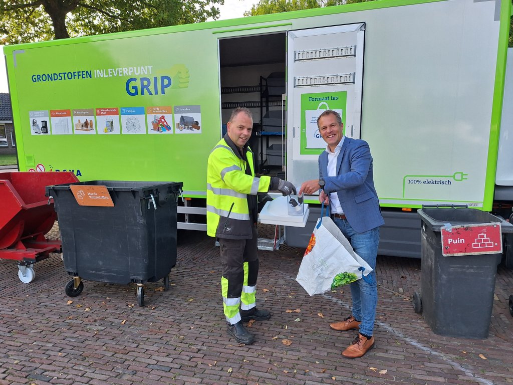 Wethouder Bos levert een boodschappentas met afval in bij de GRIP-wagen