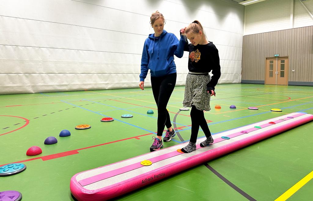 Begeleidster leidt een deelnemer aan SpecialGym  over een speciale loopmat.