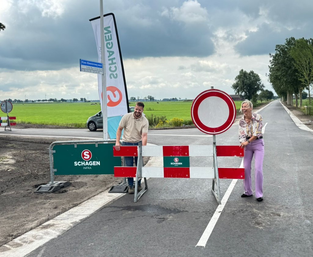 Wethouder Brinkman schuift een afzetbord opzij als opening van de vernieuwde weg.