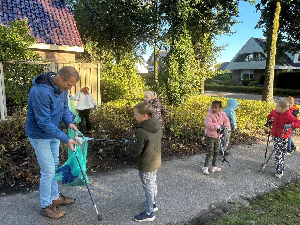 De wethouder ruimt samen met schoolkinderen zwerfafval op