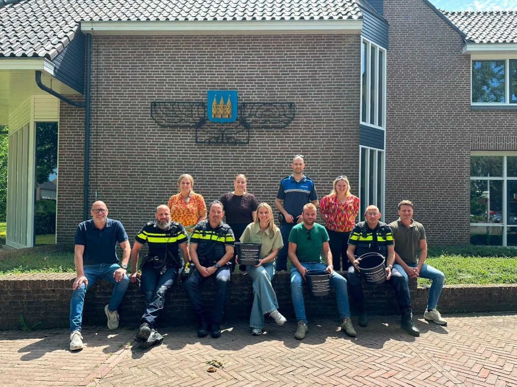 Groepsfoto van medewerkers van de politie, de provincie Overijssel en de gemeente Staphorst voor het gemeentehuis
