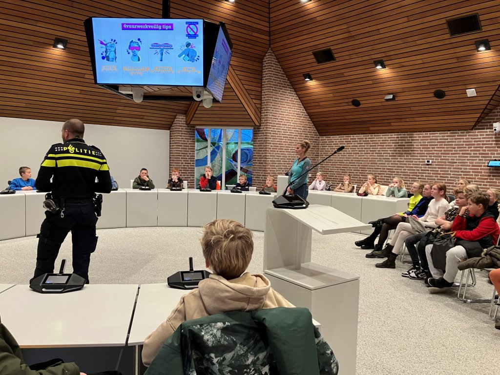 Kinderen in een kring met agent en ambulancemedewerker in het midden.