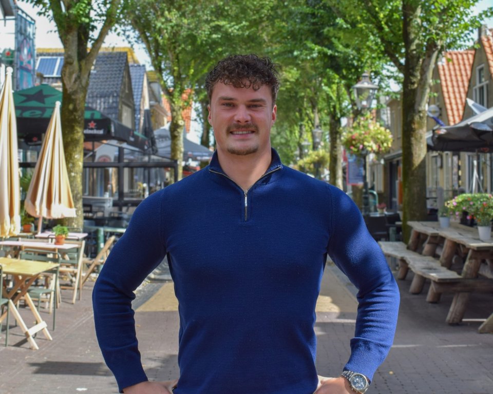 Tjardi staat in de straat met cafés in Midsland en kijkt in de camera