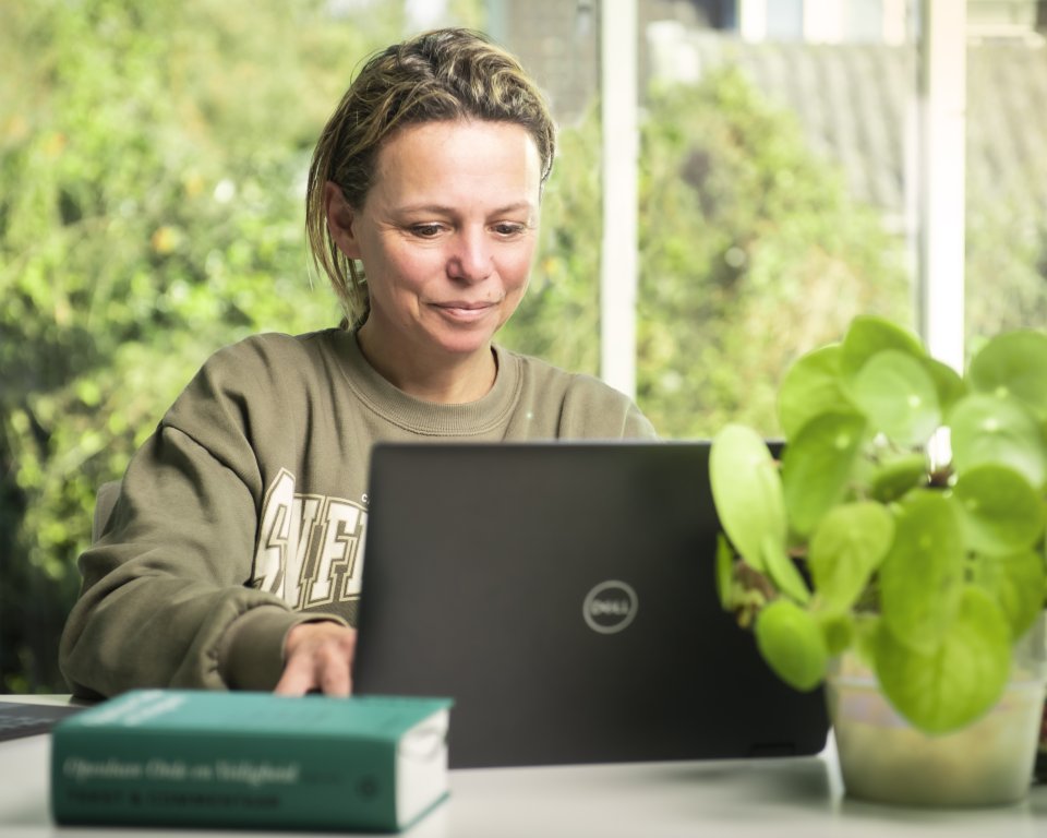 Iemand achter de computer op het gemeentehuis van Terschelling met een wetboek op tafel