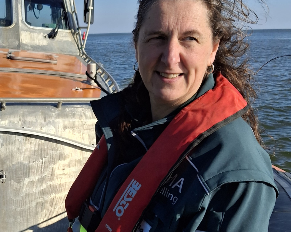Portretfoto: Jolanda Bakker zit op een boot op zee met haar SIGMA-kleding aan tijdens een oefening