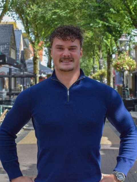 Tjardi staat in de straat met cafés in Midsland en kijkt in de camera