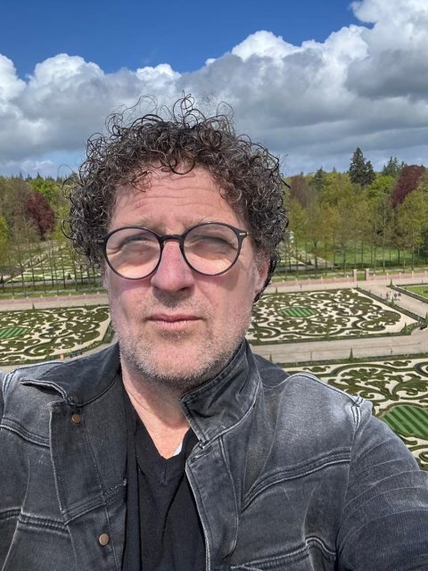 Zelfportret van Klaas Kielstra met een tuin en bomen op de achtergrond