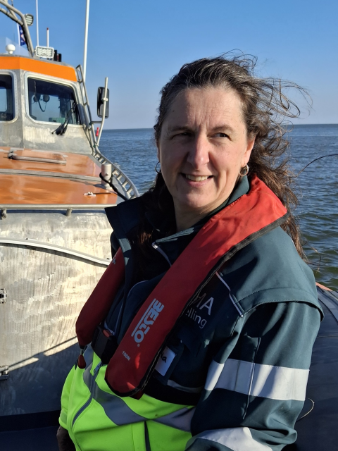 Portretfoto: Jolanda Bakker zit op een boot op zee met haar SIGMA-kleding aan tijdens een oefening