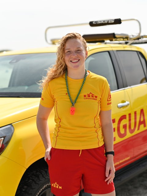 Lifeguard Demi op het strand van West aan Zee, met de KNRM-auto op de achtergrond