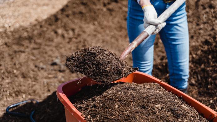Vrouw schept compost in kruiwagen