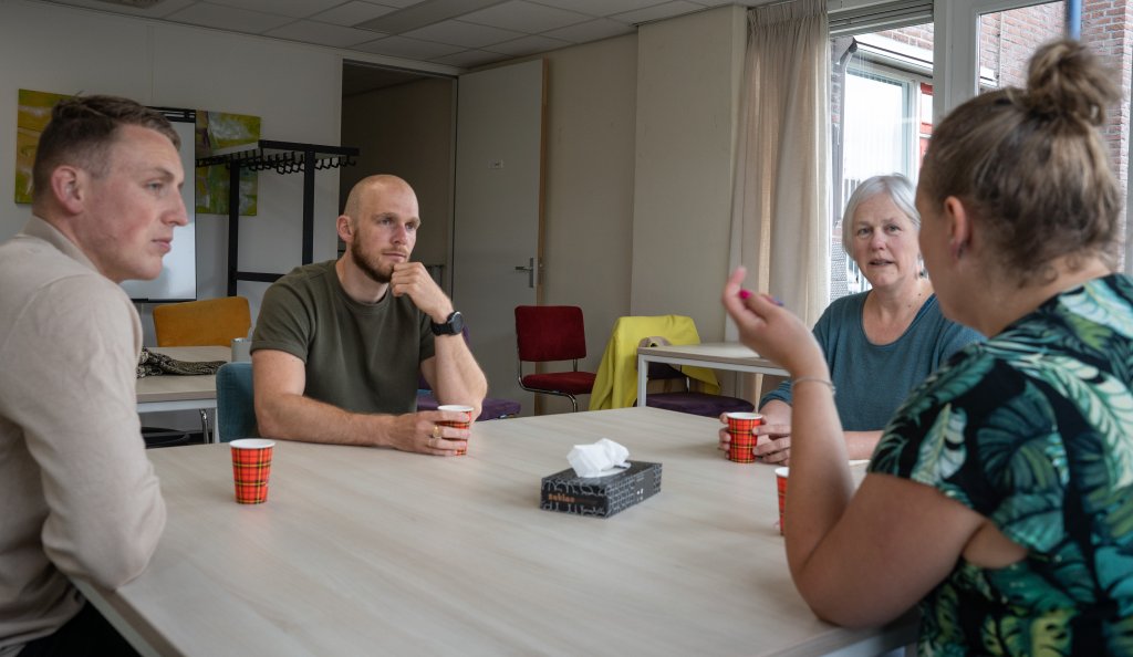 Inwoners die aan tafel met elkaar in gesprek zijn met iemand van buurtbemiddeling