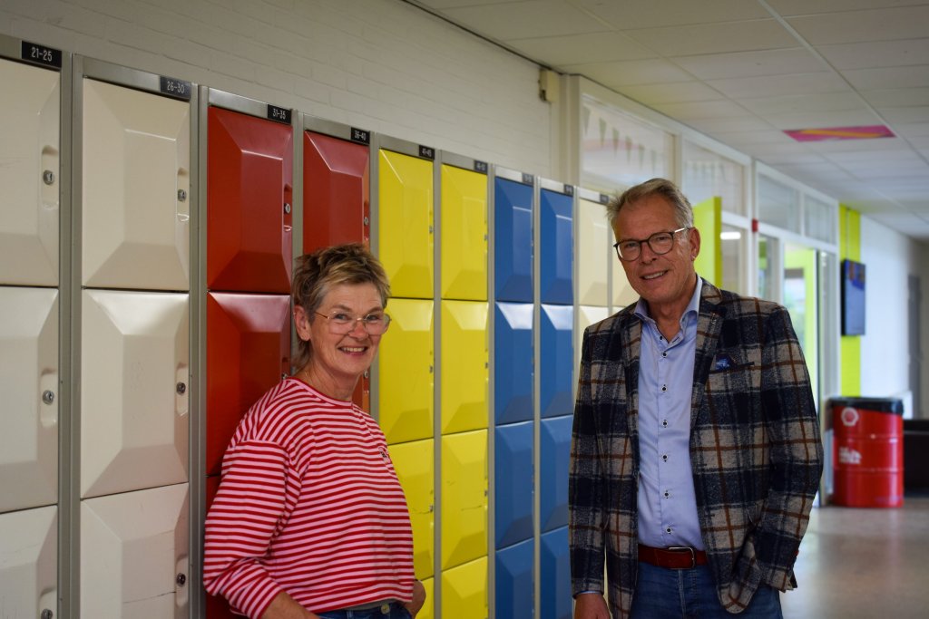 Jan staat met een collega voor de kluisjes van de school