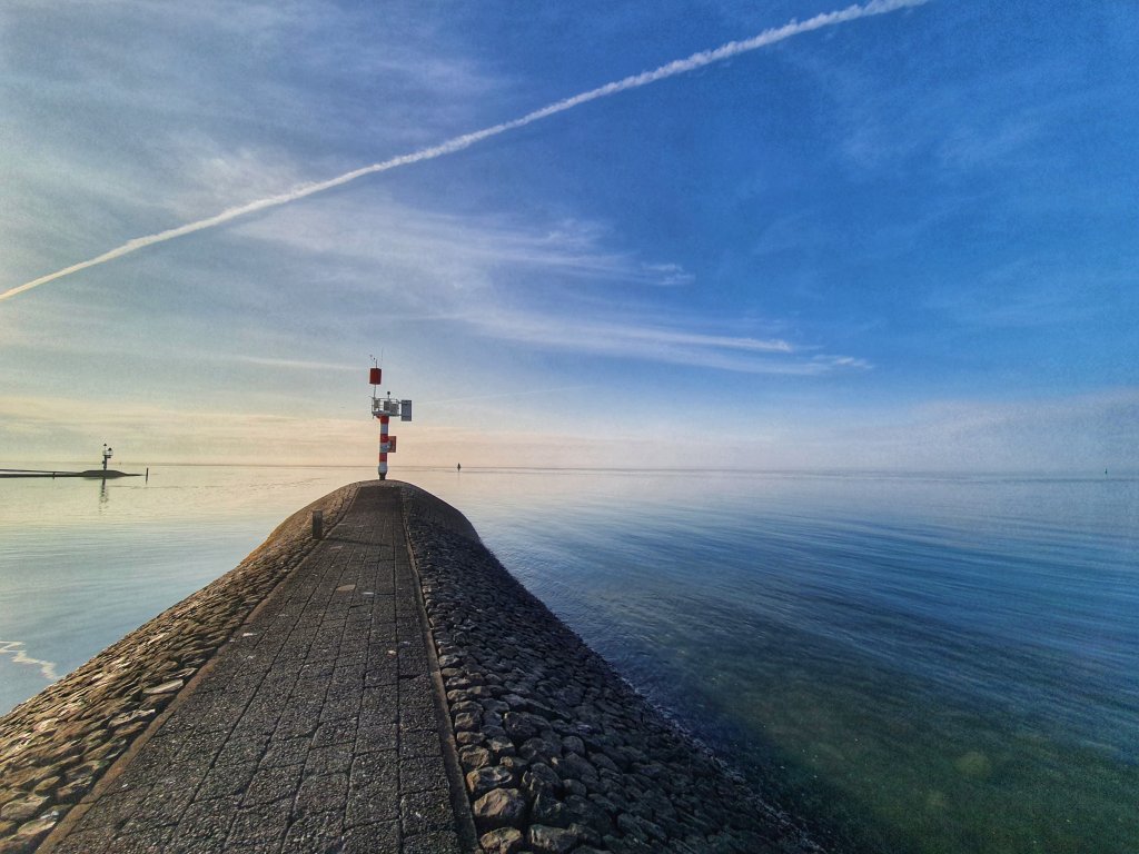 Uitzicht over de Waddenzee op Terschelling, met een stenen pier die het water in loopt