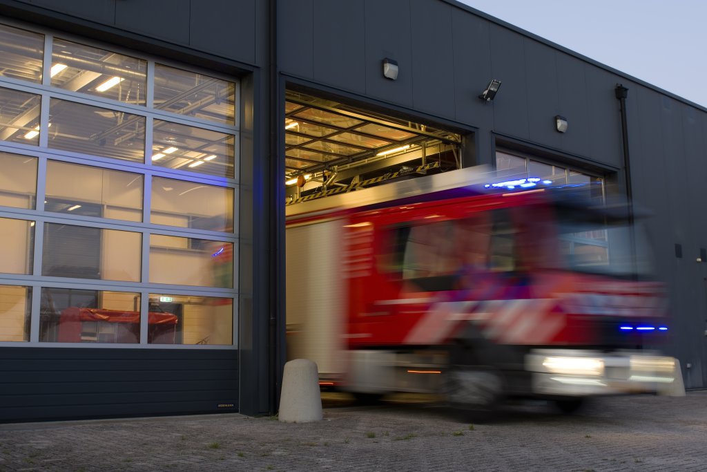 Brandweerwagen die de kazerne uit rijdt