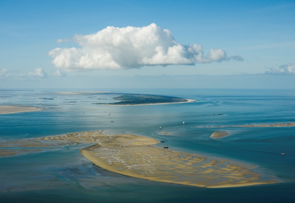 Luchtfoto van de Waddenzee met droogvallende zandplaten, vaargeulen en zeilboten