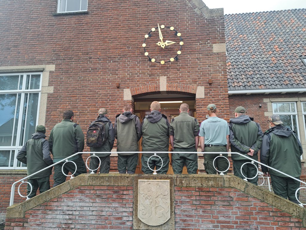 De groep medewerkers van Binnenwerk staan met de rug naar de camera opgesteld op de stap voor het gemeentehuis van Terschelling.