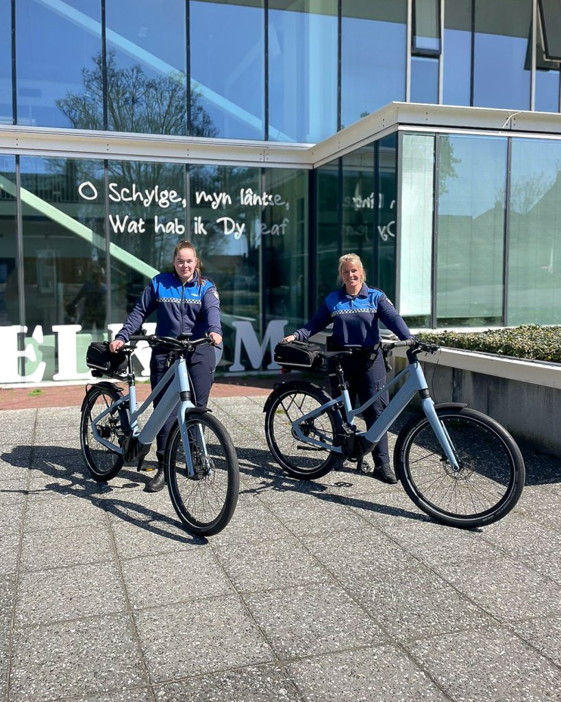 Twee vrouwelijke boa's met hun fiets voor de ingang van het gemeentehuis