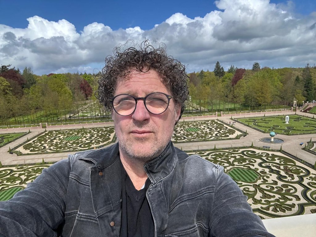 Zelfportret van Klaas Kielstra met een tuin en bomen op de achtergrond