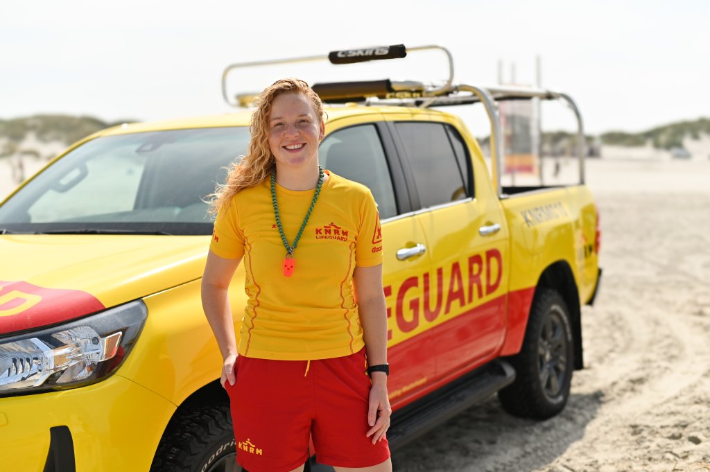 Lifeguard Demi op het strand van West aan Zee, met de KNRM-auto op de achtergrond