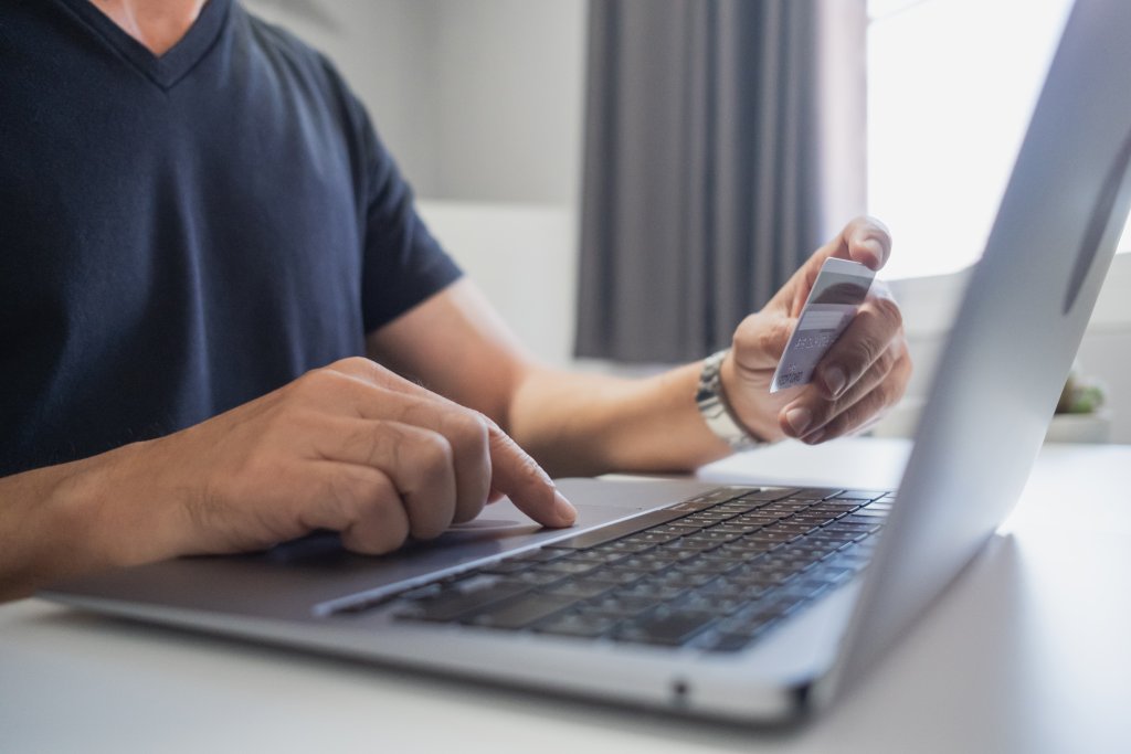 Man die met een bankpas achter zijn laptop zit