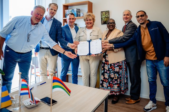 Zeven burgemeesters die op een rij staan, waarbij de middelste vrouwelijke burgemeester de intentieverklaring in haar handen houdt.