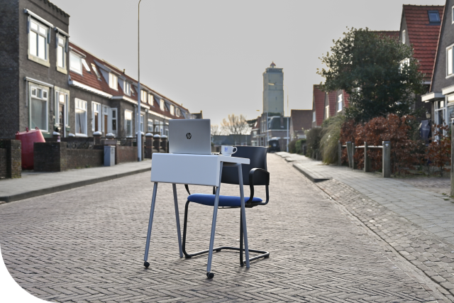 Bureau met een stoel en laptop in een straat met op de achtergrond de Brandaris 