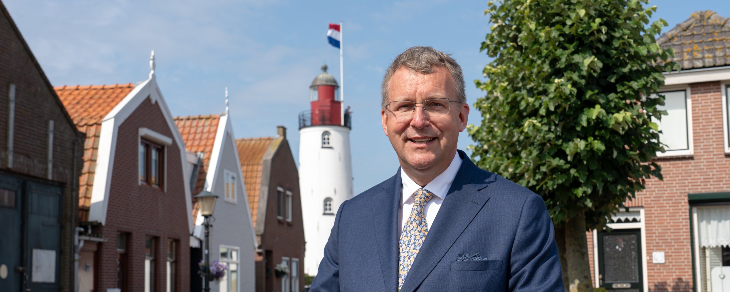 Portret foto van de nieuwe burgemeester van Urk Bart Jaspers Faijer. Op de achtergrond is de welbekende vuurtoren van Urk in beeld