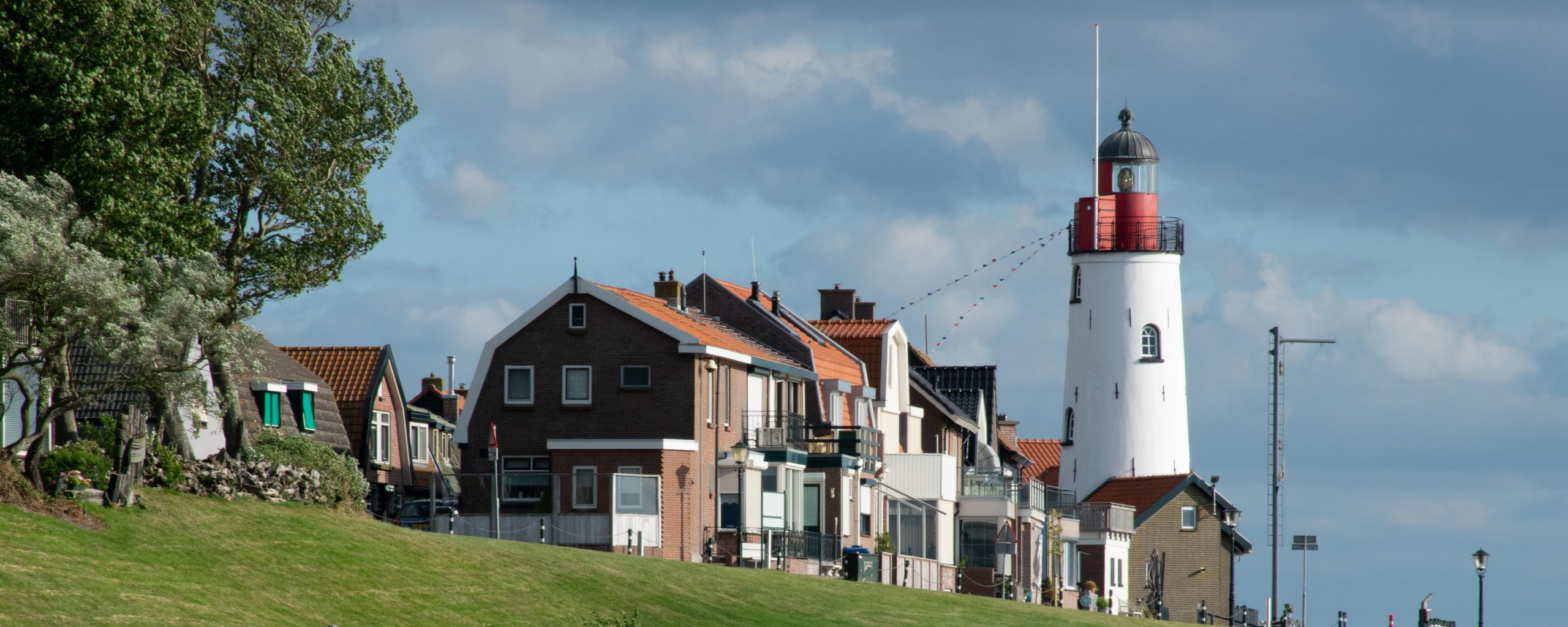 Aanzicht op de witte vuurtoren van Urk met huizen op de voorgrond.