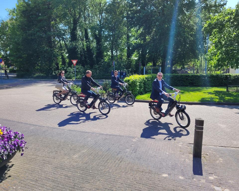 Wethouder Gerrit Post met collega-wethouders en zijn vrouw op de e-scooter tijdens zijn afscheid