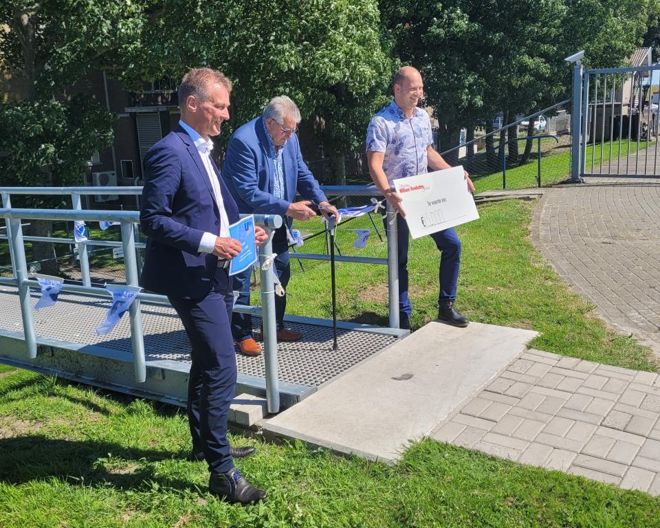 Wethouder Freek Brouwer met een cheque bij de nieuwe loopbrug bij de jachthaven op Urk