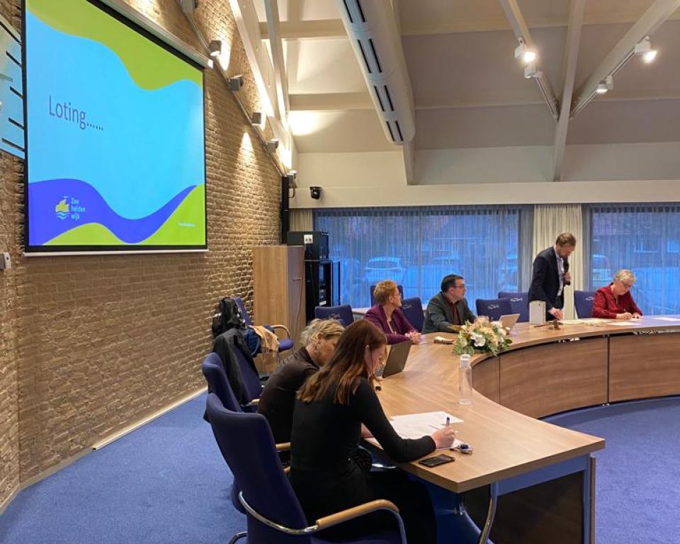 Medewerkers van de gemeente Urk zitten in de raadzaal 