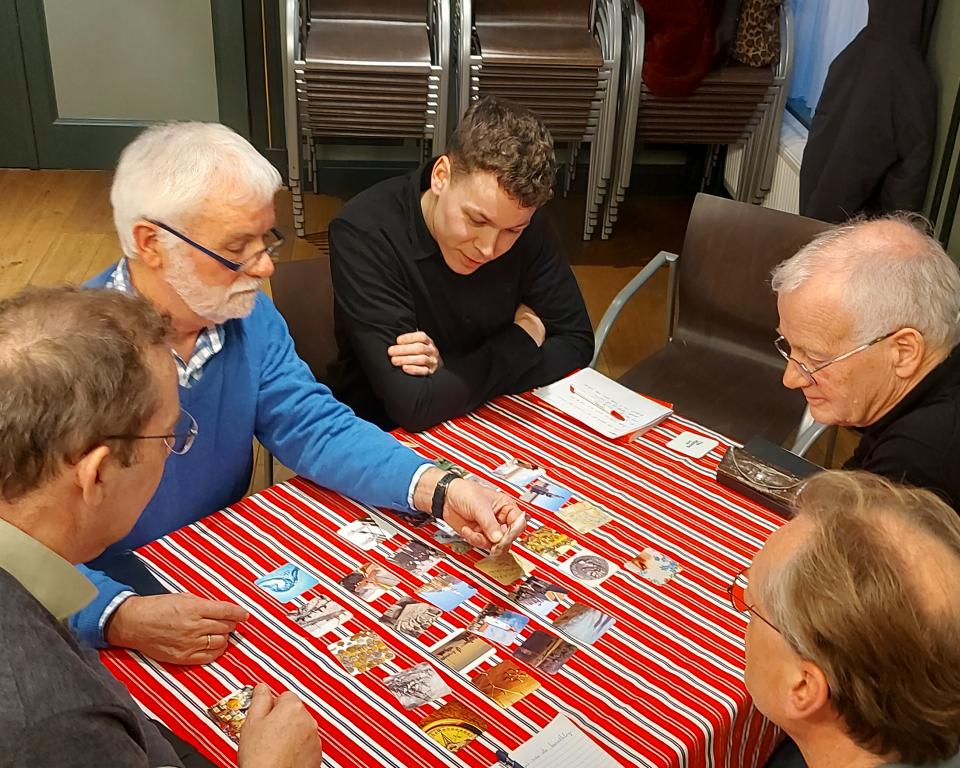 Aantal mannen aan tafel met plaatjes van Urk