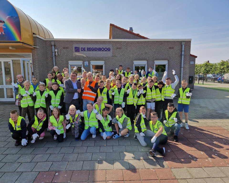 Leerlingen van de Basisschool De Regenboog voor schoolgebouw, samen met Willem Foppen
