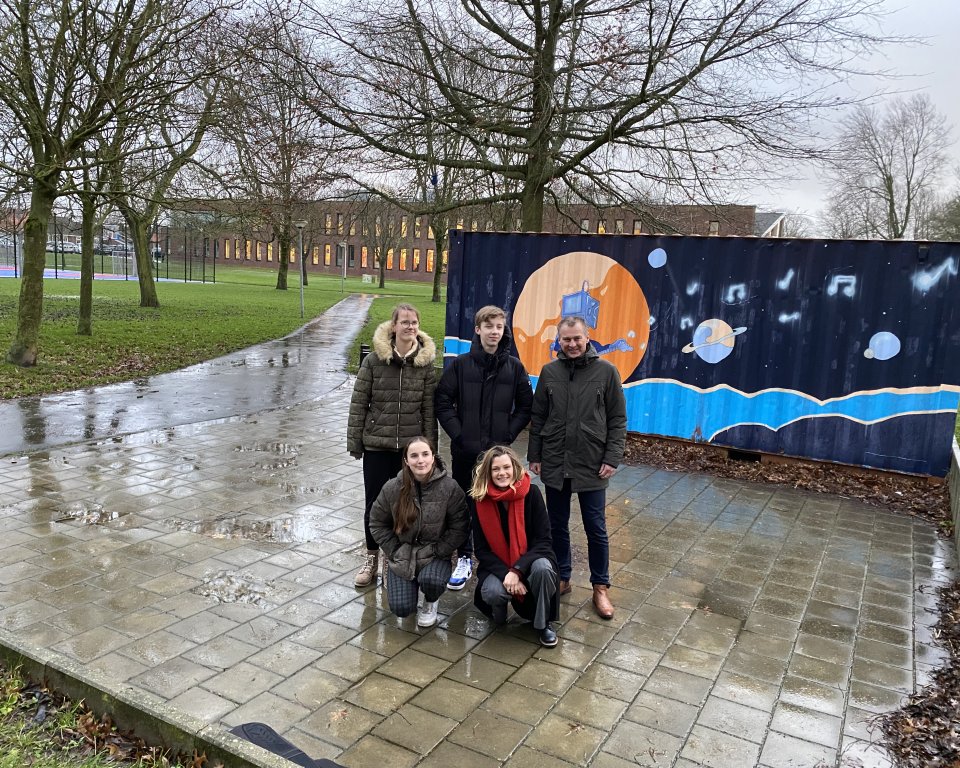 Wethouder Freek brouwer staat voor een beschilderde container met een aantal jonge kunstenaars