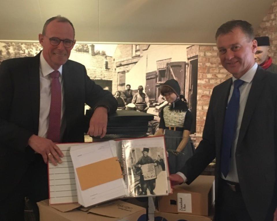 Interim museumcoördinator Jan Verhoeff  neemt de fotocollectie van de gemeente Urk in ontvangst na overhandiging van een fotoalbum uit handen van wethouder Freek Brouwer. 