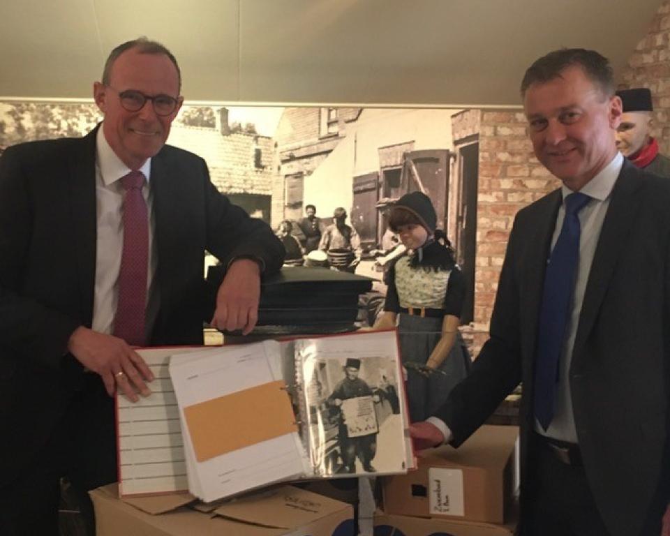 Interim museumcoördinator Jan Verhoeff neemt de fotocollectie van de gemeente Urk in ontvangst na overhandiging van een fotoalbum uit handen van wethouder Freek Brouwer.