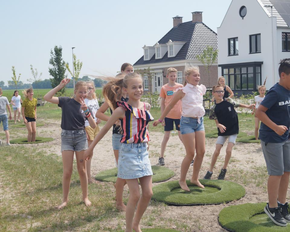 Jonge kinderen springen op stuitergras, aangelegd in het Julianaplantsoen op Urk