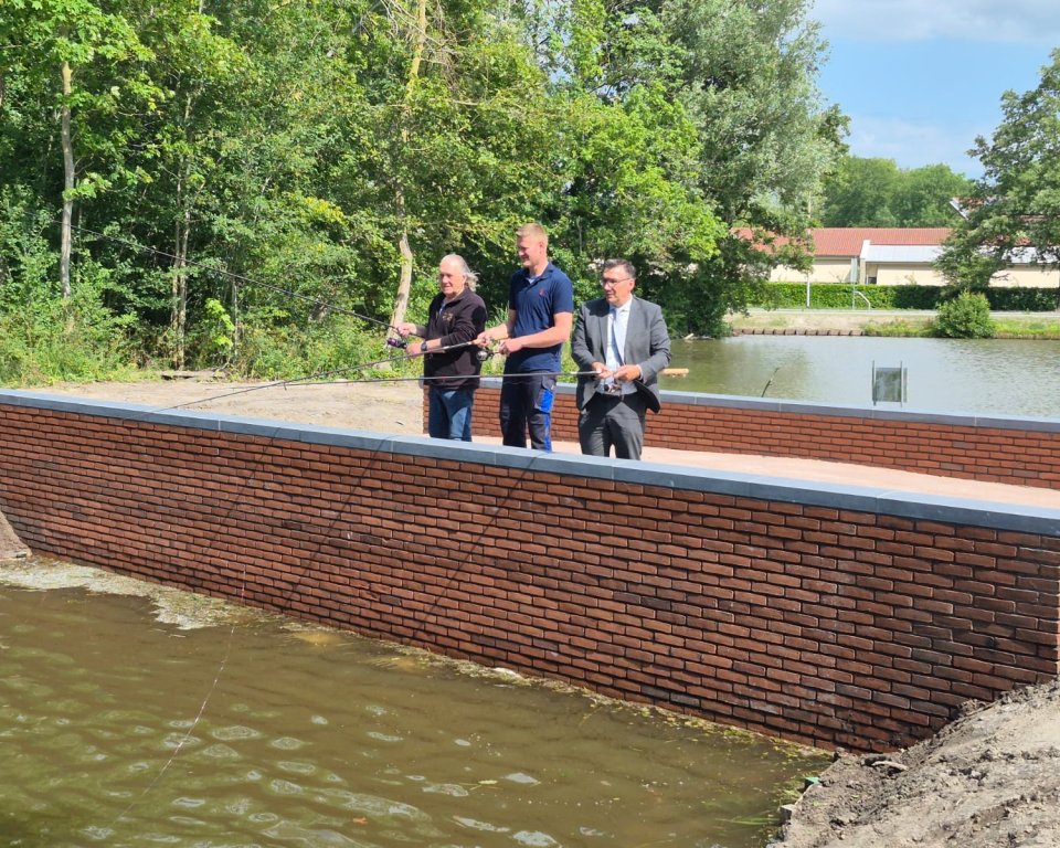 De wethouder, buurtbewoner en een lid van de hengelsportvereniging openen samen het park. Door de hengel uit de gooien.