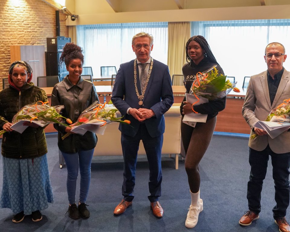 Een foto van waarnemend burgemeester Jan Westmaas met 4 nieuwe Nederlanders die hun naturalisatieceremonie hebben afgerond en nu officieel als Nederlanders worden herkent.