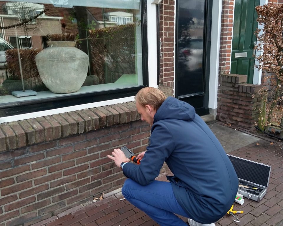 Man hurkt voor een huis, gereedschap